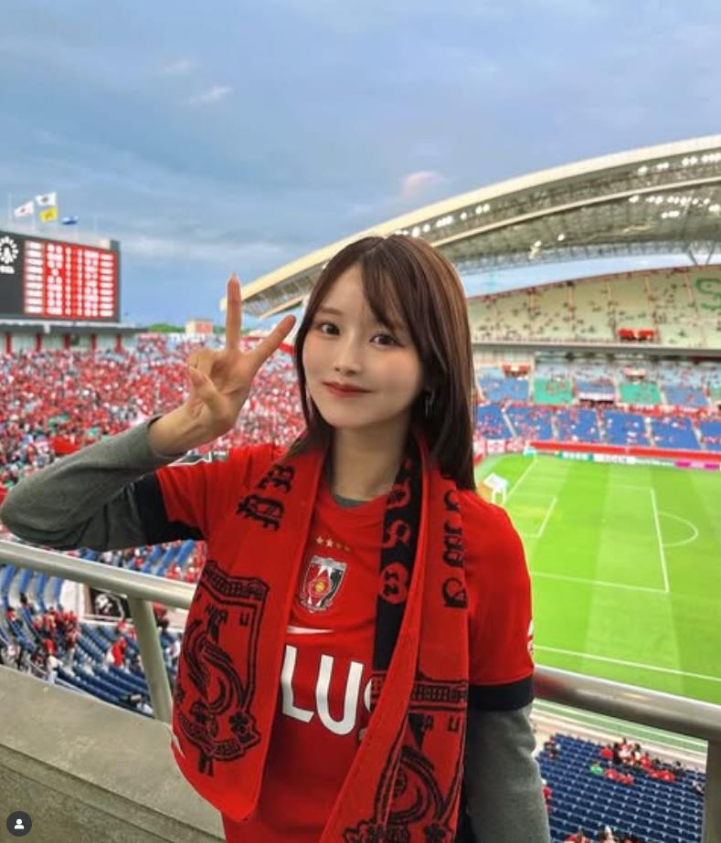 Fan nữ Urawa đây rồi! Gương mặt đỏ bừng mỉm cười dưới ánh hoàng hôn, mái tóc đen lay động trong gió, vòng eo thon thả.