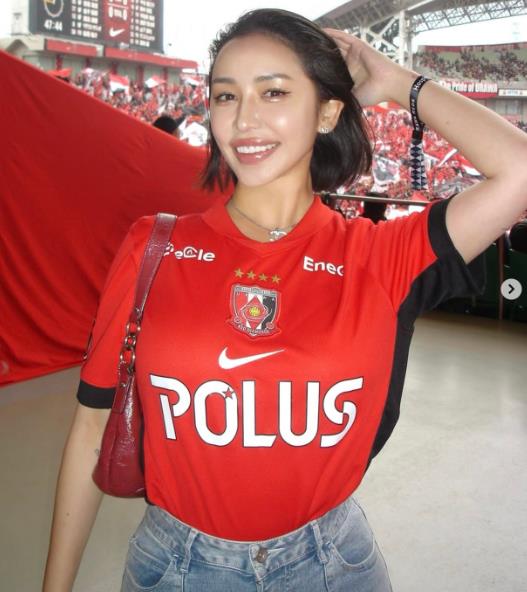Fan nữ Urawa đây rồi! Gương mặt đỏ bừng mỉm cười dưới ánh hoàng hôn, mái tóc đen lay động trong gió, vòng eo thon thả.