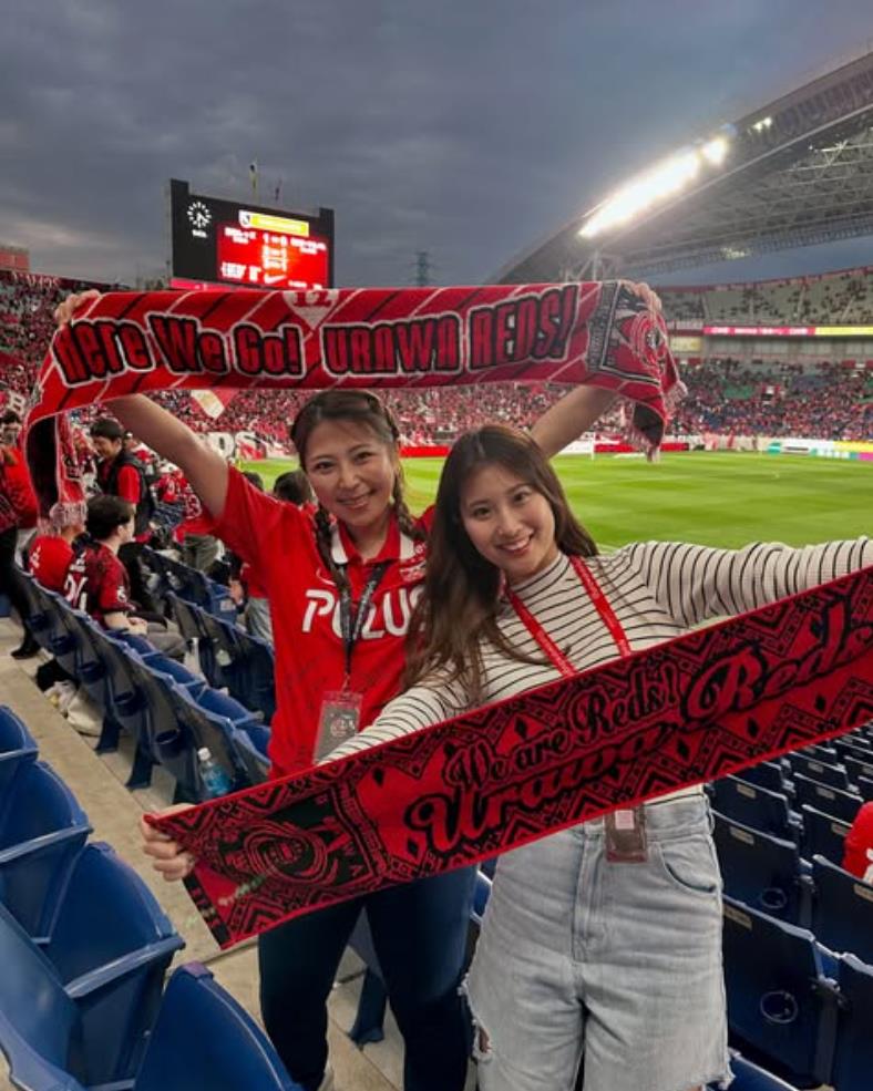 Fan nữ Urawa đây rồi! Gương mặt đỏ bừng mỉm cười dưới ánh hoàng hôn, mái tóc đen lay động trong gió, vòng eo thon thả.